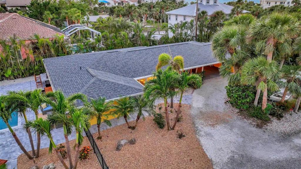 An aerial view of a house with a gray shingled roof, palm trees, and gravel driveway — 2795 A N BEACH ROAD UNIT #A, ENGLEWOOD, FL