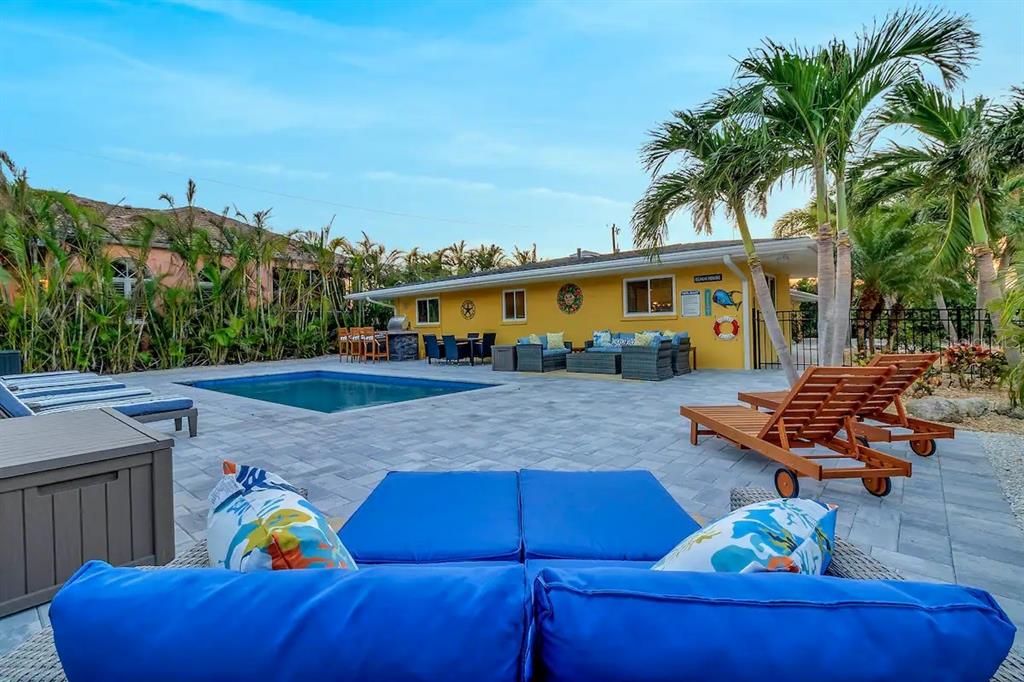 A backyard patio features a swimming pool, lounge chairs, and a yellow house exterior — 2795 A N BEACH ROAD UNIT #A, ENGLEWOOD, FL