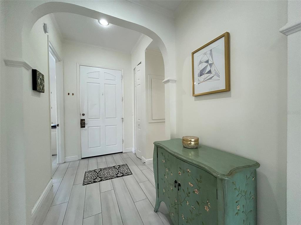 A white entryway features a green painted cabinet, a patterned rug, and arched architectural details — 3705 54TH DRIVE W UNIT 201, BRADENTON, FL