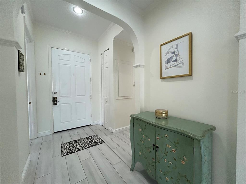 An entryway features a white door, light wood-look tile flooring, and a green painted cabinet — 3705 54TH DRIVE W UNIT 201, BRADENTON, FL