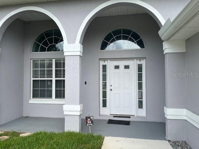 The exterior of a house features a gray facade, arched entryways, and a white front door — 23 RIDLEY LANE UNIT B, PALM COAST, FL