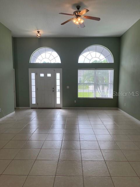 A spacious room with light-colored tile flooring, a ceiling fan, and arched windows — 23 RIDLEY LANE UNIT B, PALM COAST, FL