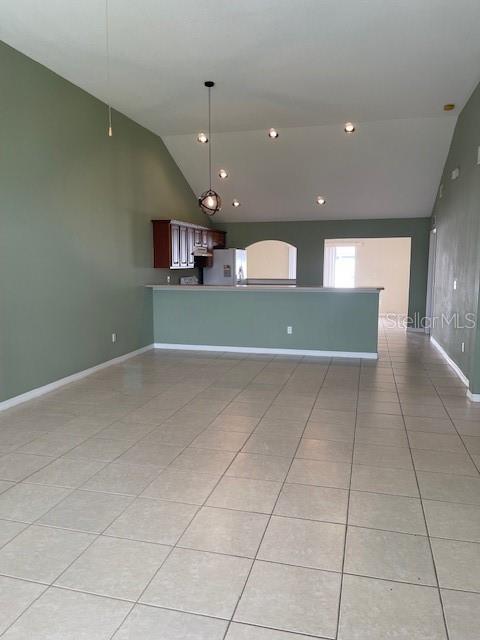 A spacious room features light-colored tile flooring, a vaulted ceiling, and a kitchen breakfast bar — 23 RIDLEY LANE UNIT B, PALM COAST, FL