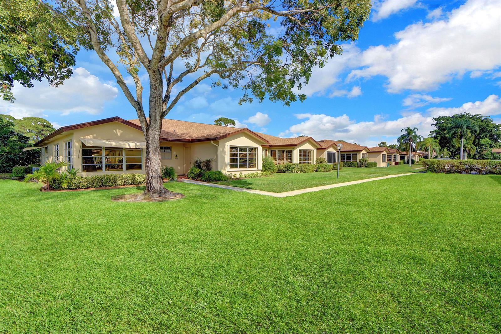 A single-story tan residential building with a large lawn and a prominent tree — 14050 Nesting Way # B, Delray Beach FL 33484, DELRAY BEACH, FL
