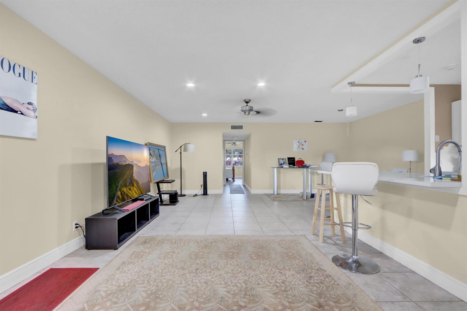 A living room with tile flooring, a television on a stand, and a breakfast bar — 14050 Nesting Way # B, Delray Beach FL 33484, DELRAY BEACH, FL