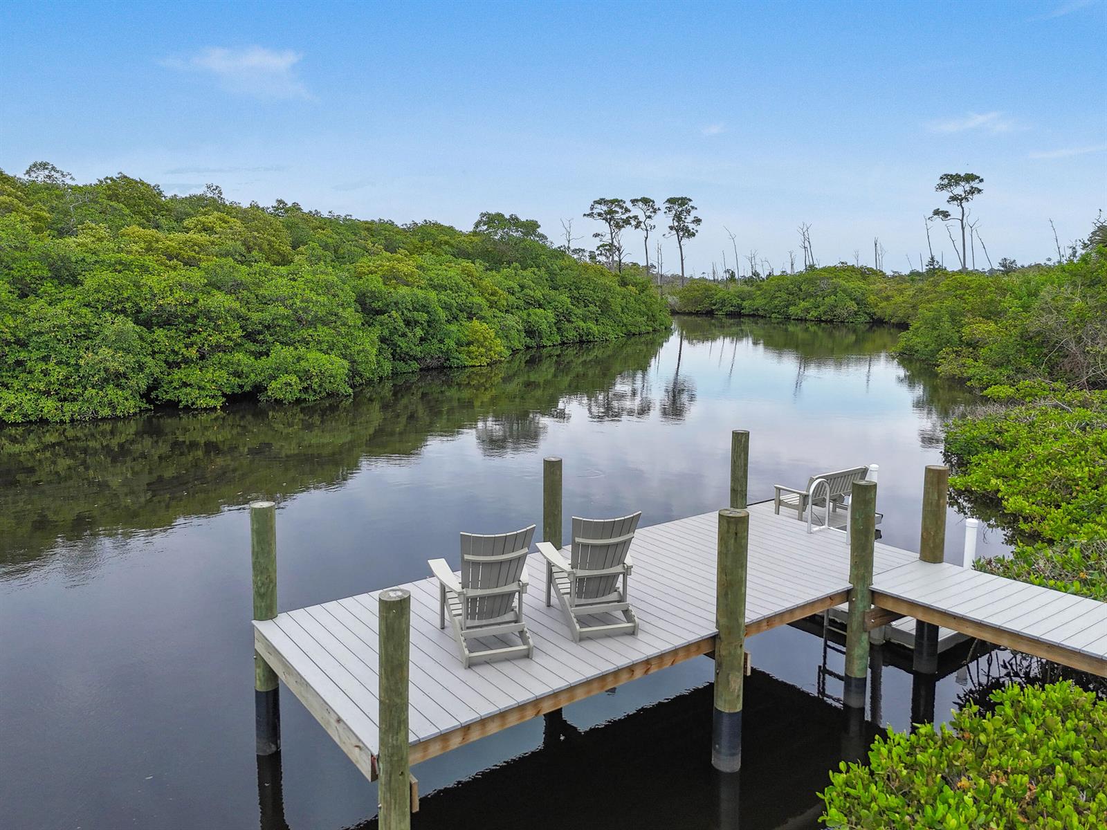 A wooden dock with two chairs sits on a calm waterway surrounded by lush mangroves — 10541 SE Le Parc, Jupiter FL 33469, JUPITER, FL