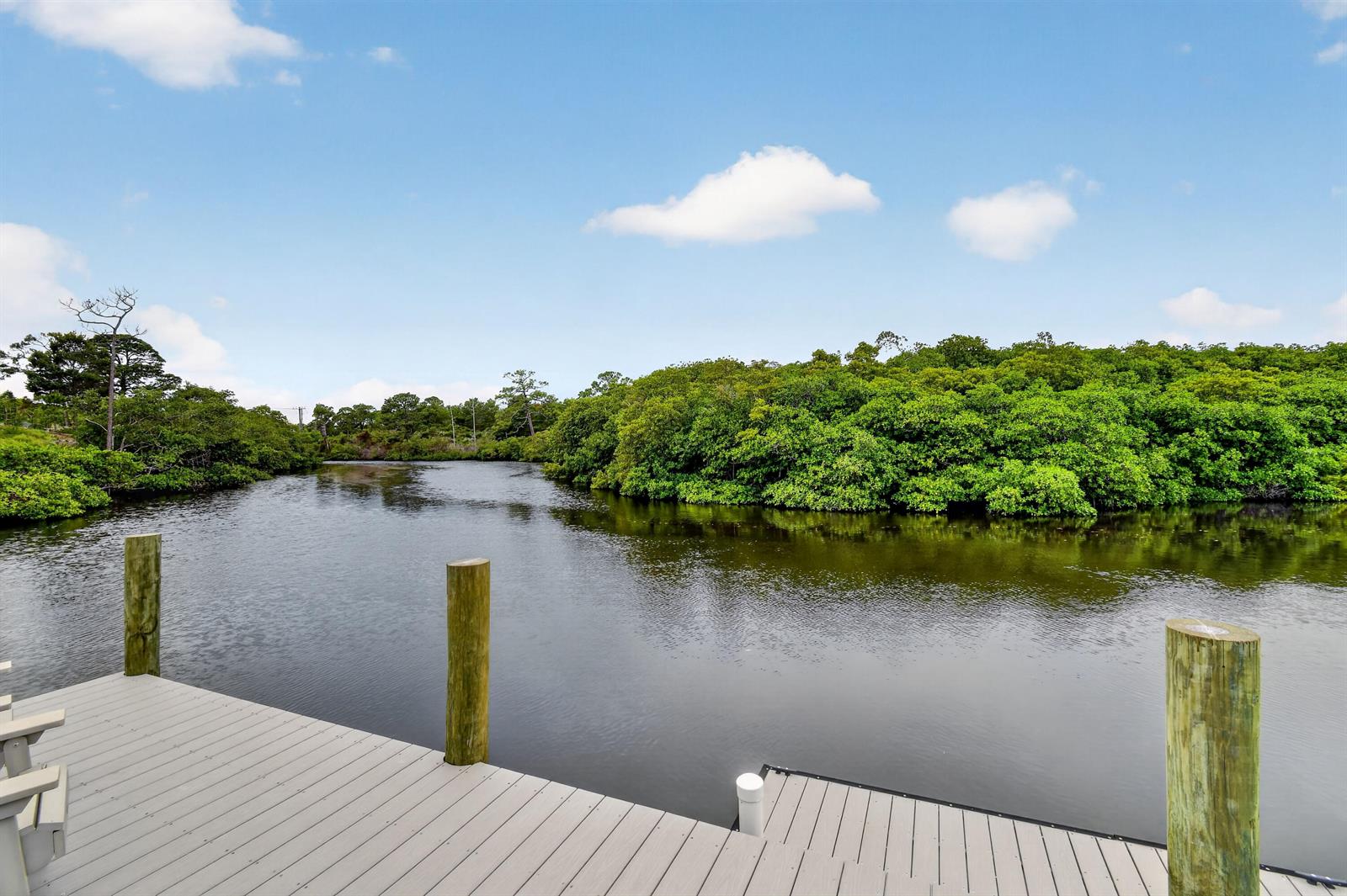 A wooden dock overlooks a calm, dark waterway surrounded by dense green trees and mangroves — 10541 SE Le Parc, Jupiter FL 33469, JUPITER, FL