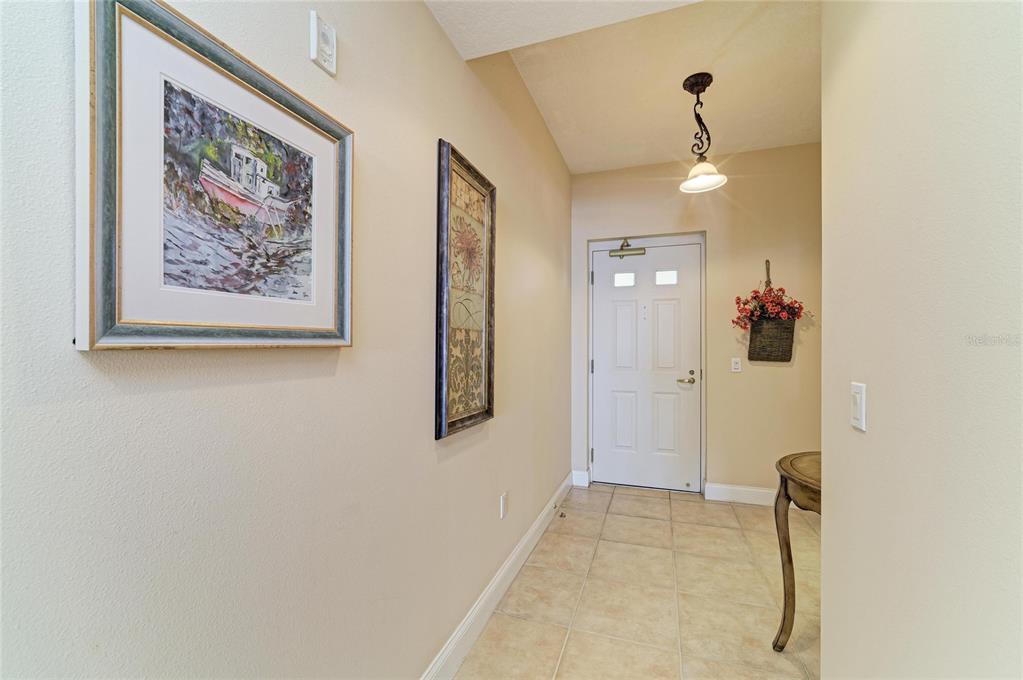A tiled entryway features a white front door, two framed wall pictures, and a light fixture — 611 RIVIERA DUNES WAY UNIT 403, PALMETTO, FL