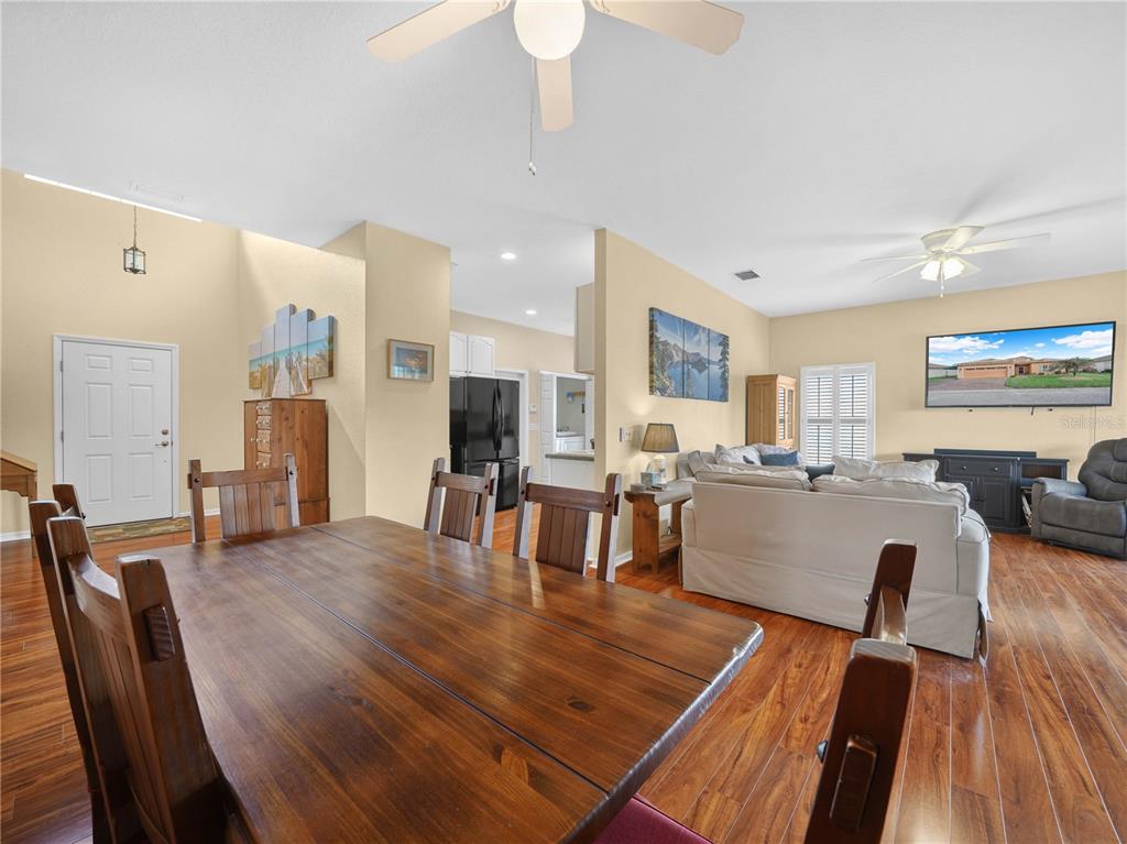 A dining area with a wooden table opens into a living room with light walls — 4144 ABERDEEN LANE, LAKE WALES, FL