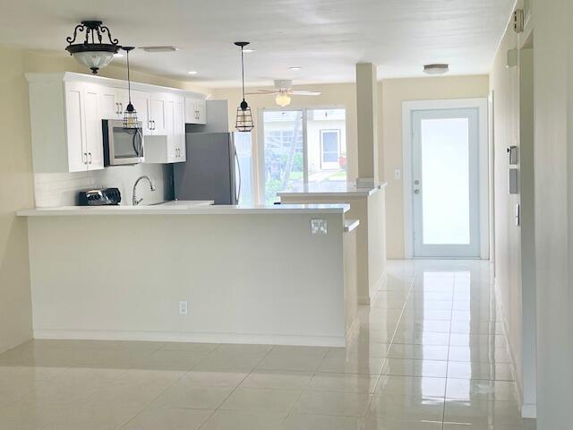 A kitchen with white cabinets, stainless steel appliances, and a breakfast bar on tiled floors — 13757 Flora Place # A, Delray Beach FL 33484, DELRAY BEACH, FL