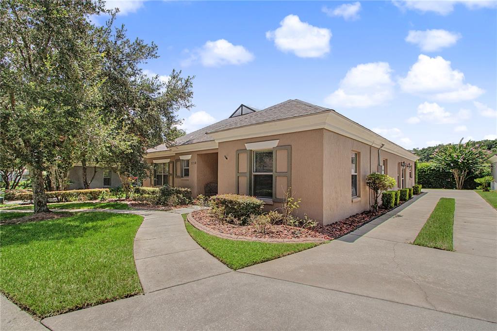A tan stucco house with a concrete driveway and a curved walkway leading to the entrance — 1718 SE 28TH STREET, OCALA, FL