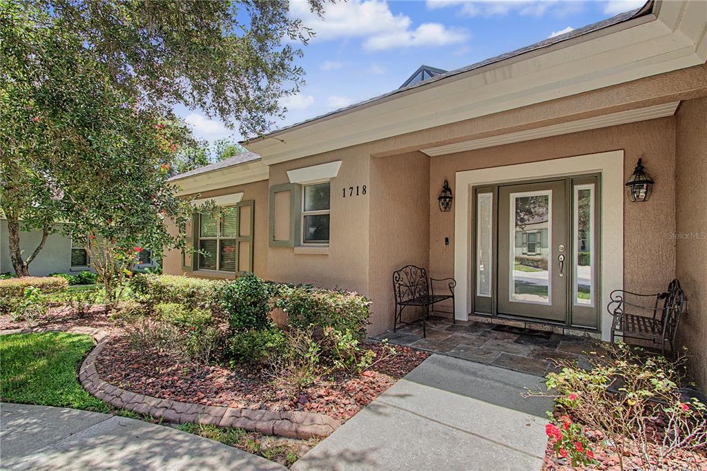 The exterior of a house features a tan stucco facade, a front door, and landscaping — 1718 SE 28TH STREET, OCALA, FL