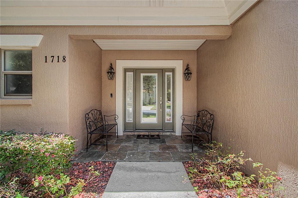 A front entryway features a paved porch, two black metal benches, and a glass-paneled door — 1718 SE 28TH STREET, OCALA, FL