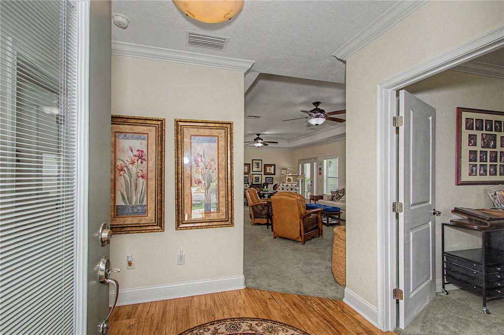 An entryway with wood flooring leads into a carpeted living area with two framed pictures — 1718 SE 28TH STREET, OCALA, FL