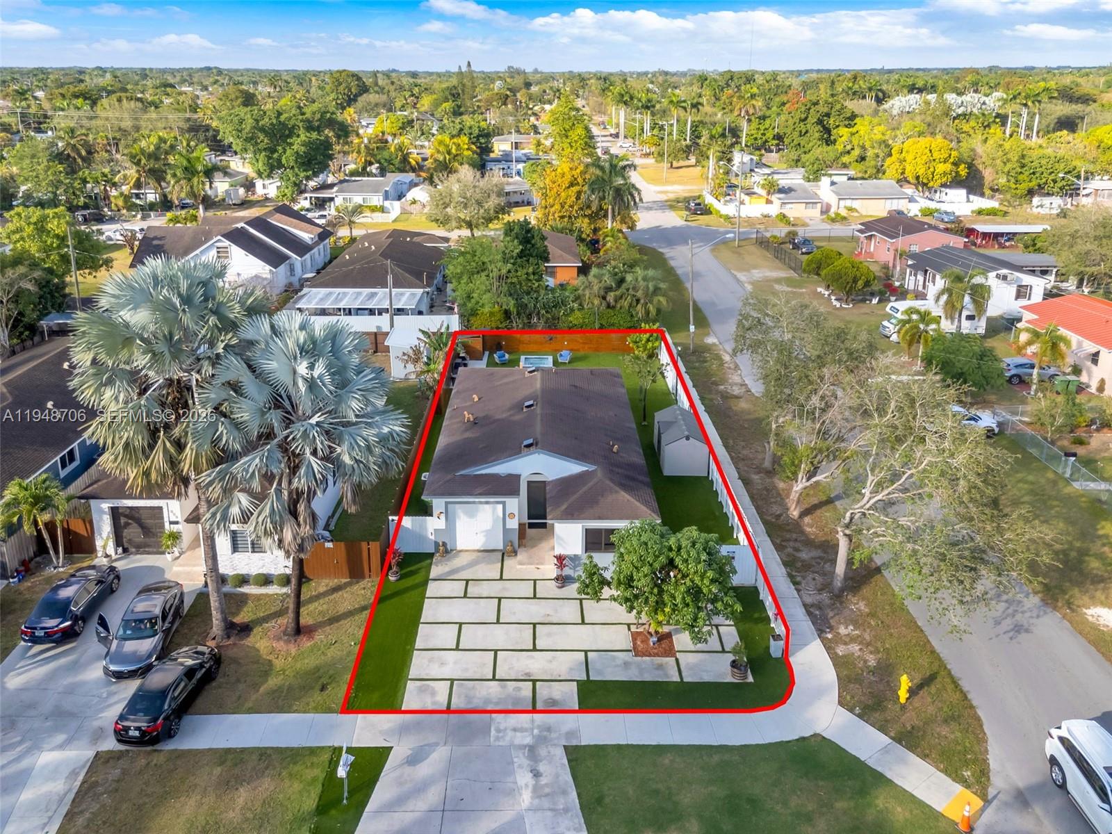 An aerial view shows a single-story house with a paved driveway and fenced backyard — 407 NW 9th Ct, Homestead FL 33030, HOMESTEAD, FL