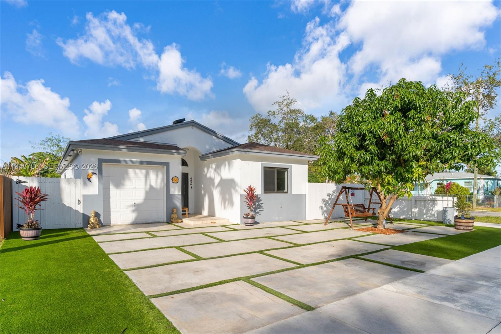 A single-story house with a white facade, a garage, and a paved driveway with grass — 407 NW 9th Ct, Homestead FL 33030, HOMESTEAD, FL