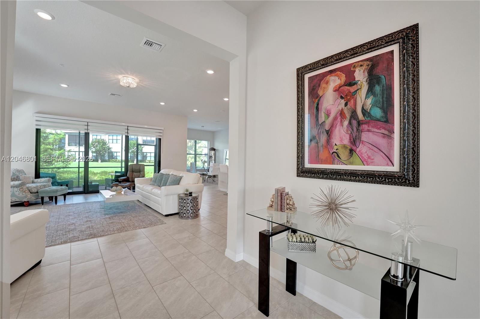A bright living room features tile floors, a white sofa, and a glass console table — 21982 Canadensis Cir # 101, Boca Raton FL 33428, BOCA RATON, FL