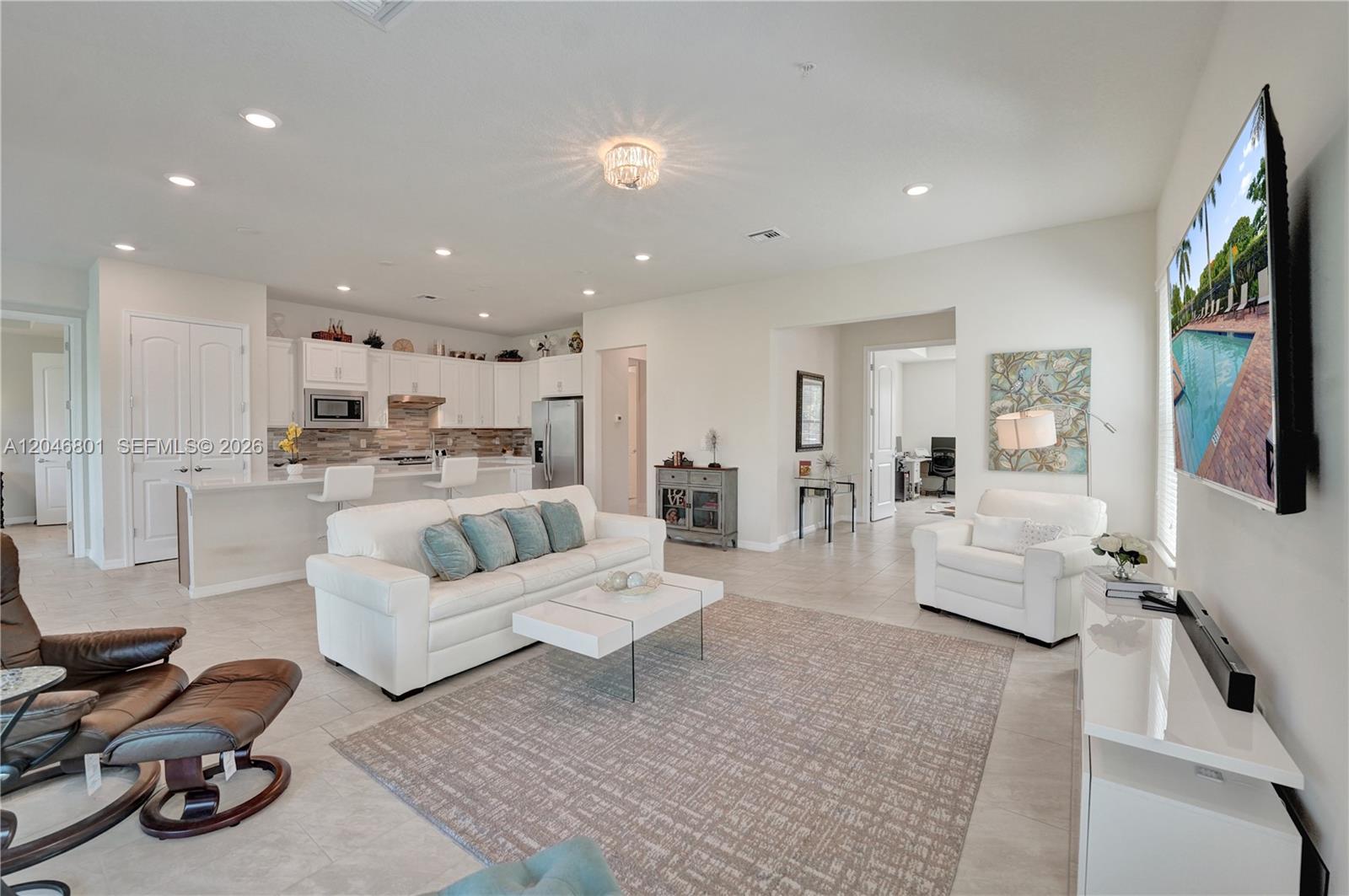 A bright, open-concept living room features a white sofa, a brown recliner, and a kitchen — 21982 Canadensis Cir # 101, Boca Raton FL 33428, BOCA RATON, FL