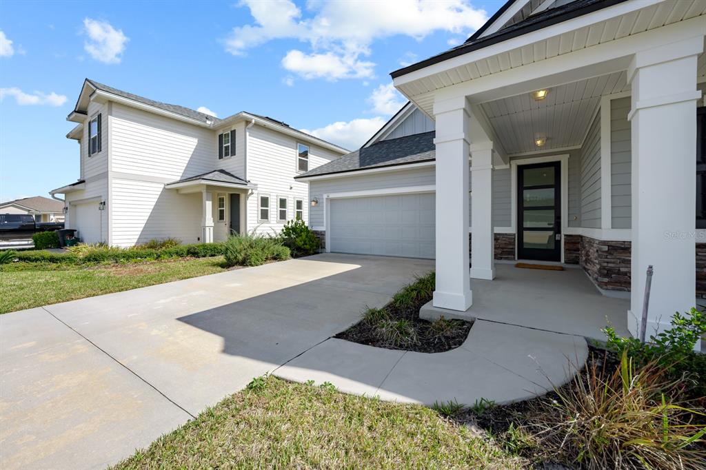 A view of a house exterior featuring a concrete driveway, garage, and covered front porch — 41 LOS LAGOS BOULEVARD, PALM COAST, FL