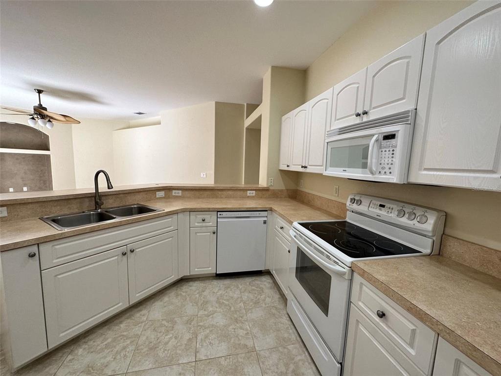 A kitchen features white cabinets, laminate countertops, a white electric range, and a double sink — 3643 SPINNER AVENUE, NORTH PORT, FL