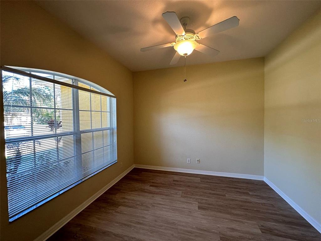 An empty room features light-colored walls, wood-look flooring, a ceiling fan, and a large window — 3643 SPINNER AVENUE, NORTH PORT, FL
