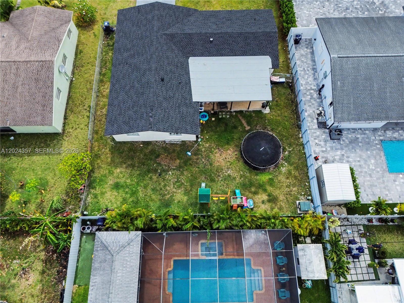 An aerial view shows a house with a backyard, trampoline, playground, and a screened pool — 16912 SW 107th Pl, Miami FL 33157, MIAMI, FL
