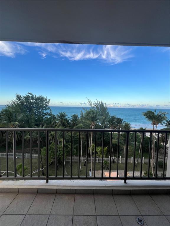 A balcony with a metal railing overlooks a beach, palm trees, and the ocean — 4745 ISLA VERDE AVENUE UNIT 8-C, CAROLINA, PR