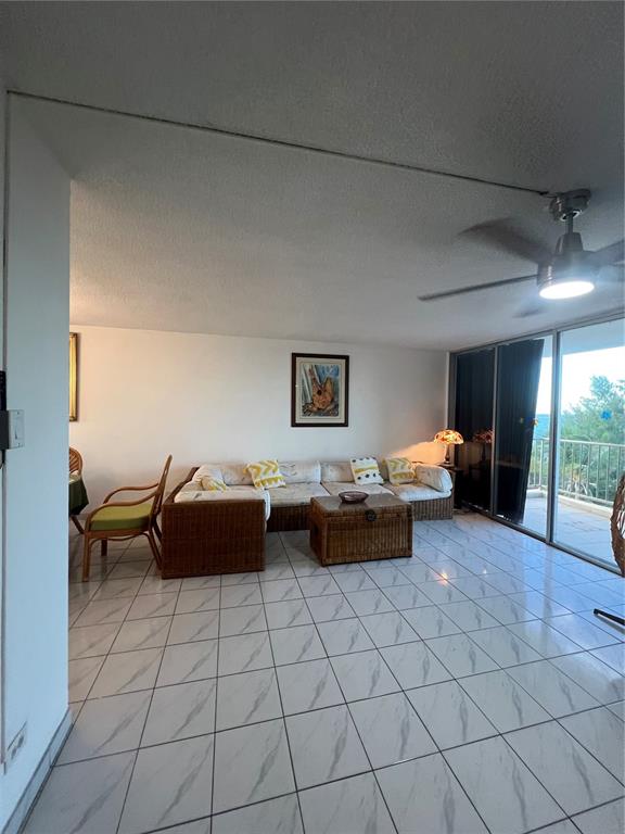 A living room features white tile floors, a wicker sectional sofa, and a ceiling fan — 4745 ISLA VERDE AVENUE UNIT 8-C, CAROLINA, PR