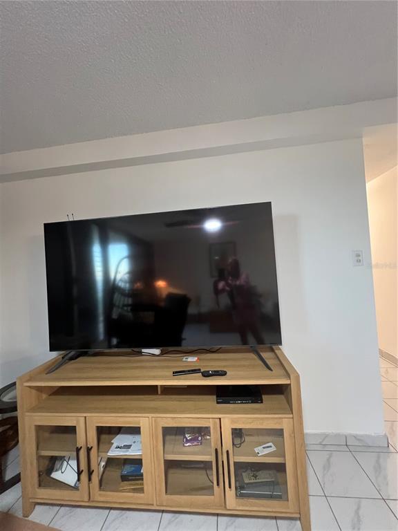 A large television sits on a light wood media console in a room with tile floors — 4745 ISLA VERDE AVENUE UNIT 8-C, CAROLINA, PR