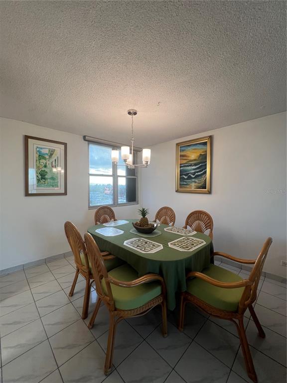 A dining room features a green-clothed table, six wicker chairs, tile floors, and two framed paintings — 4745 ISLA VERDE AVENUE UNIT 8-C, CAROLINA, PR