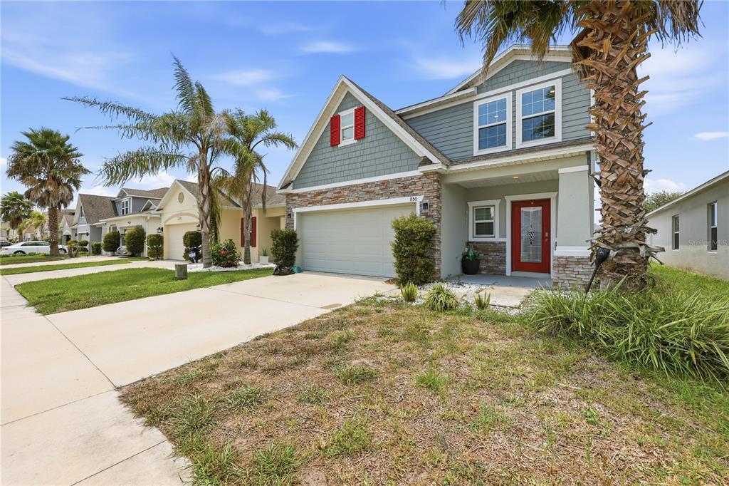 A two-story suburban house with a red front door, a garage, and palm trees — 850 BOCAVISTA COURT, DAVENPORT, FL