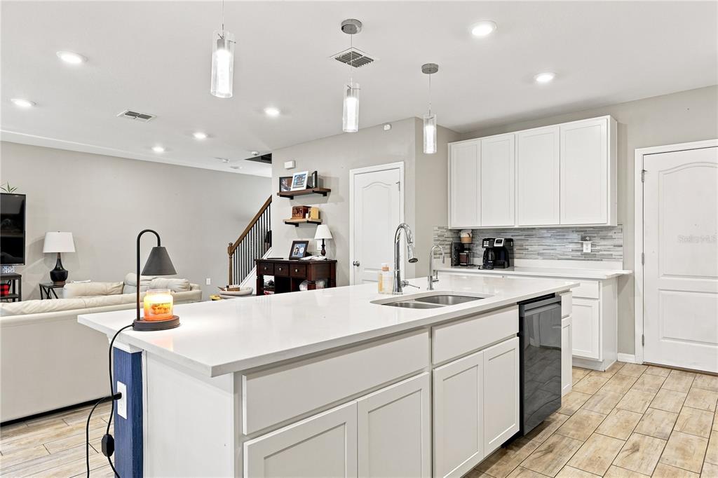 A kitchen with white cabinets, a large island with a sink, and light wood flooring — 850 BOCAVISTA COURT, DAVENPORT, FL