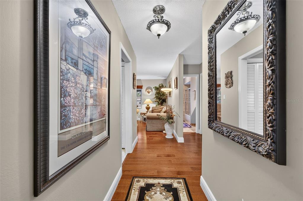 A hallway with hardwood floors, a framed print, a large ornate mirror, and ceiling lighting — 2781 ABBEY ROAD, WINTER PARK, FL