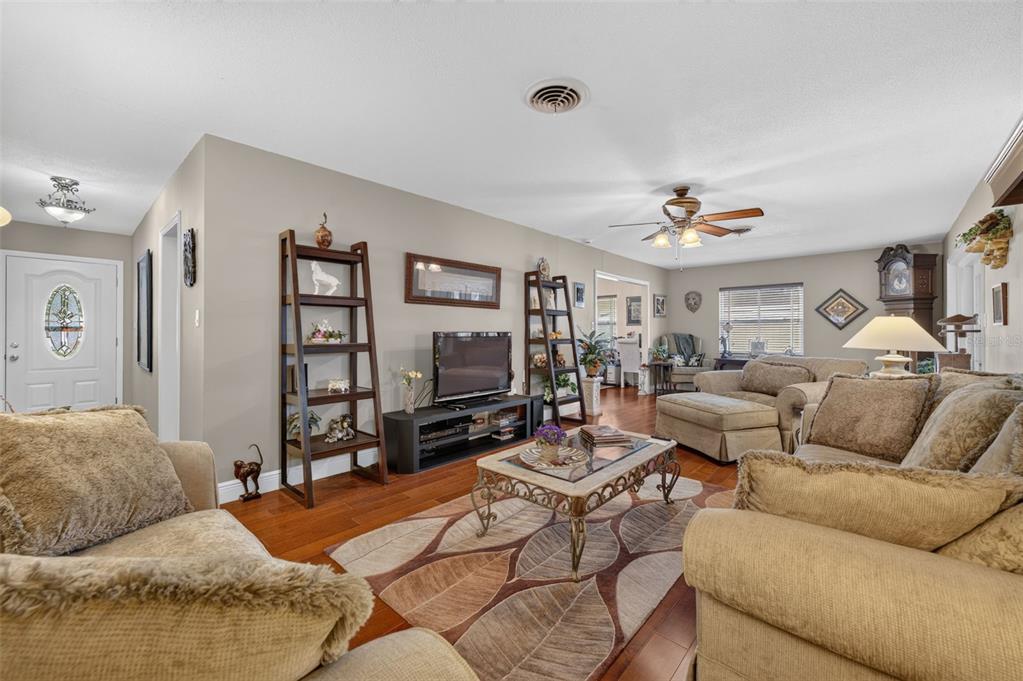 A living room features beige sofas, a coffee table, a television, and hardwood flooring — 2781 ABBEY ROAD, WINTER PARK, FL