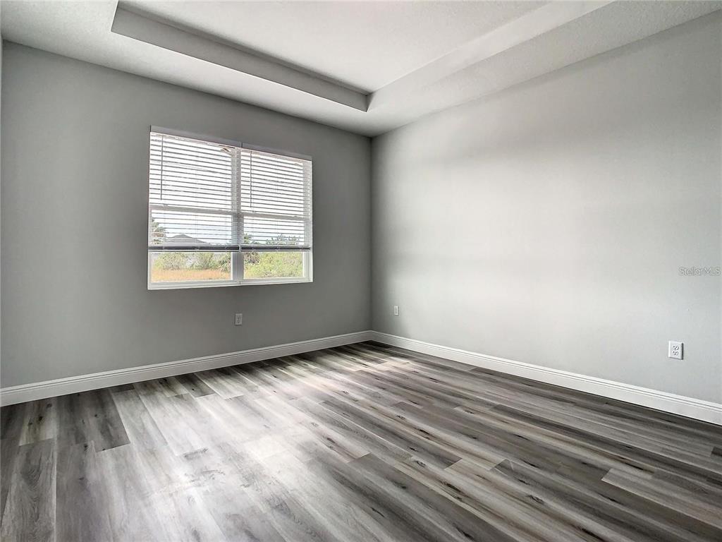 An empty room features light gray walls, wood-look flooring, and a window with blinds — 14683 INGRAHAM BOULEVARD, PORT CHARLOTTE, FL