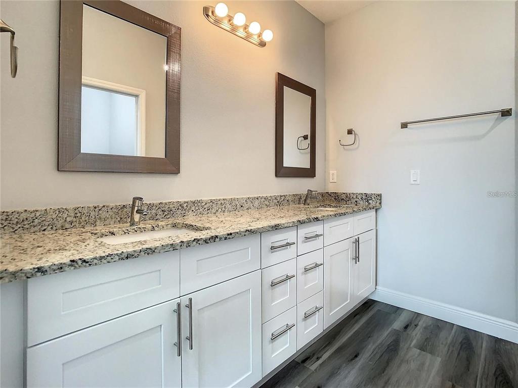 A bathroom features a double-sink granite vanity with white cabinets and two wall mirrors — 14683 INGRAHAM BOULEVARD, PORT CHARLOTTE, FL