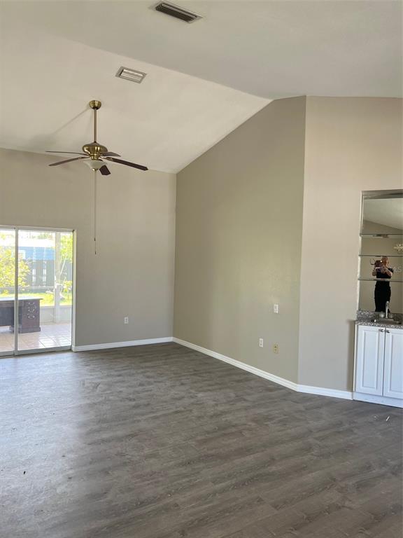 A living room with vaulted ceilings, a ceiling fan, wood-look flooring, and a wet bar — 1330 ABALOM STREET, PORT CHARLOTTE, FL