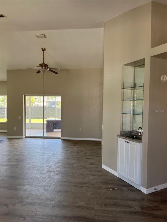 A living area with wood-look flooring, a ceiling fan, sliding glass doors, and a wet bar — 1330 ABALOM STREET, PORT CHARLOTTE, FL