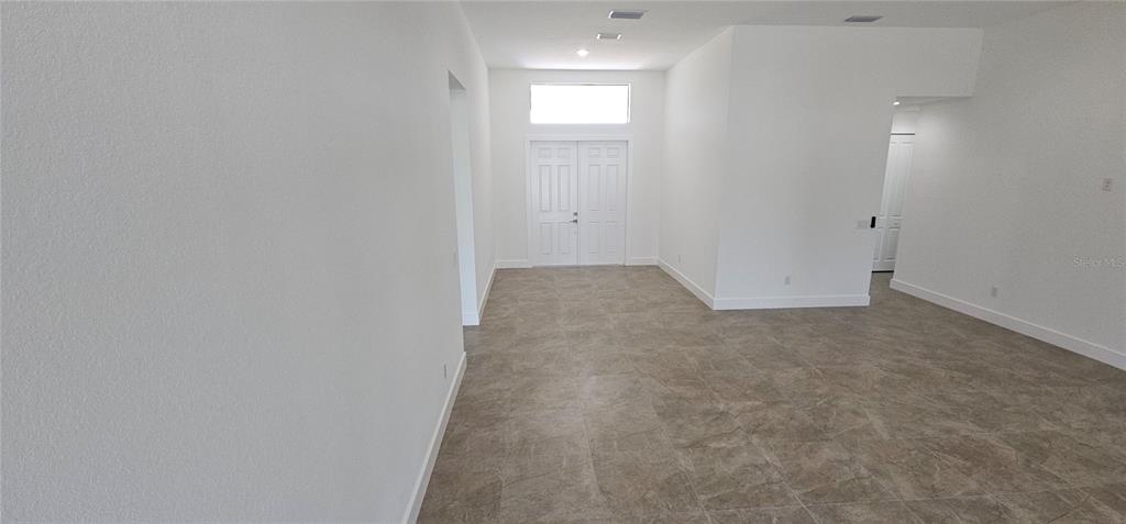 An empty room with white walls, tiled floors, and a double-door entryway with a transom window — 3413 NW 18TH STREET, CAPE CORAL, FL