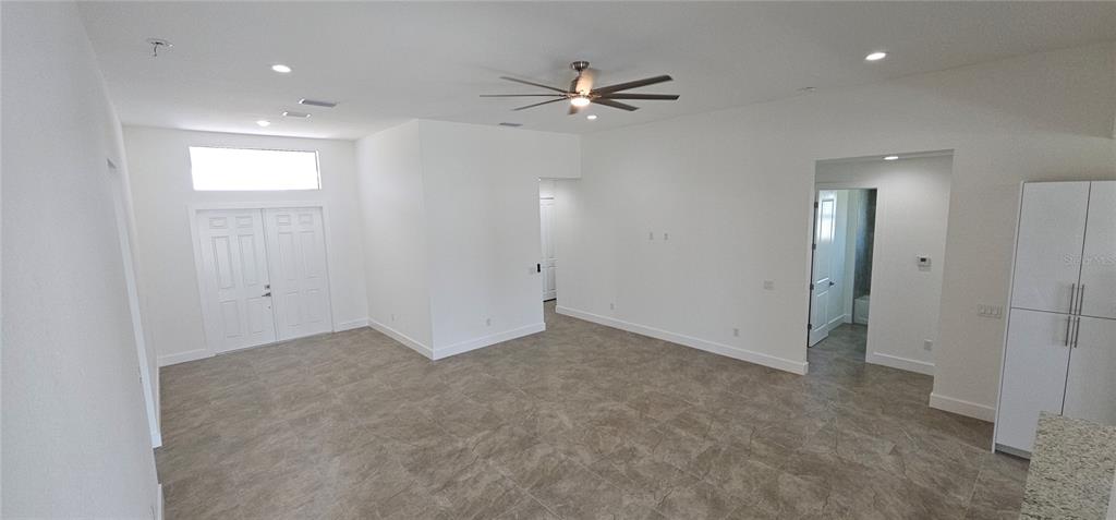 A spacious living area features white walls, tile flooring, a ceiling fan, and double doors — 3413 NW 18TH STREET, CAPE CORAL, FL