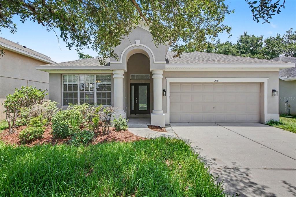 A single-story house with a beige stucco exterior, a two-car garage, and a covered entryway — 278 VENETIAN BAY CIRCLE, SANFORD, FL