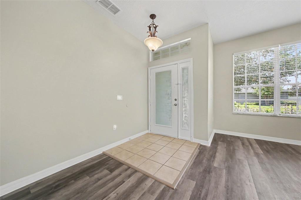 An entryway with a tiled floor, wood-look flooring, a front door, and a hanging light — 278 VENETIAN BAY CIRCLE, SANFORD, FL