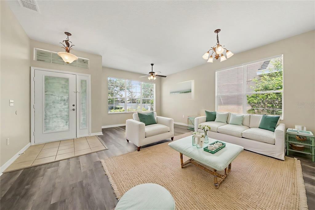 A living room features light walls, wood-look flooring, a white sofa, and a central area rug — 278 VENETIAN BAY CIRCLE, SANFORD, FL
