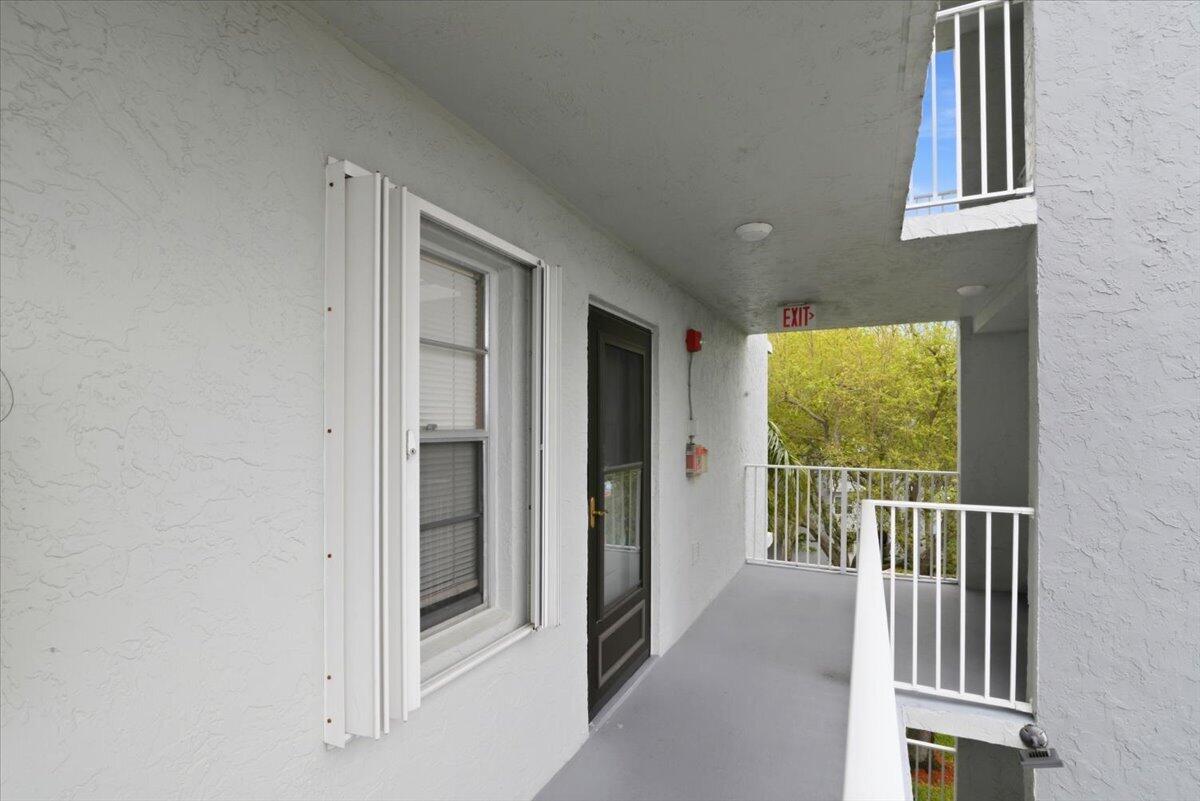 An exterior walkway with a dark door, white walls, and a white metal railing — 2220 N Cypress Bend Drive # 410, Pompano Beach FL 33069, POMPANO BEACH, FL