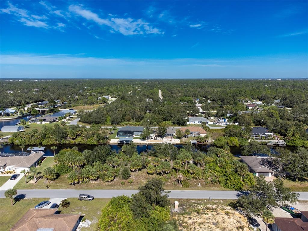 An aerial view shows a residential neighborhood with houses along a canal and dense trees — 17324 GULFSPRAY CIRCLE, PORT CHARLOTTE, FL