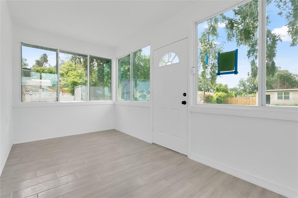 A bright sunroom features white walls, light wood-look tile flooring, and large windows — 3504 S NASHVILLE AVENUE, ORLANDO, FL