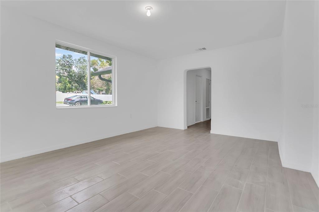 An empty room with white walls, light gray tile flooring, and a single window — 3504 S NASHVILLE AVENUE, ORLANDO, FL