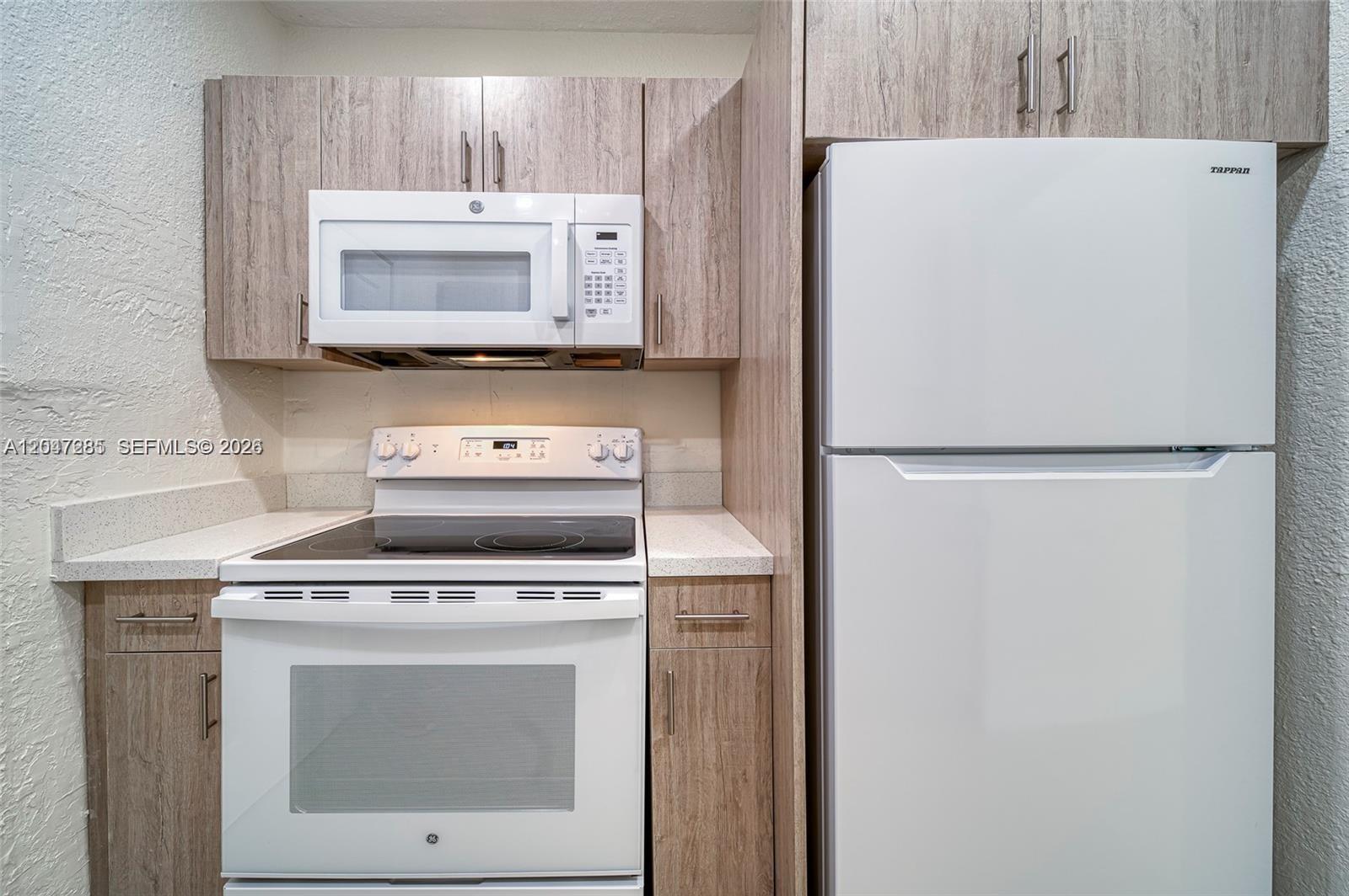 A kitchen features white appliances, light wood-grain cabinets, and light-colored countertops — 1747 NW 40th St # 1747, Miami FL 33142, MIAMI, FL