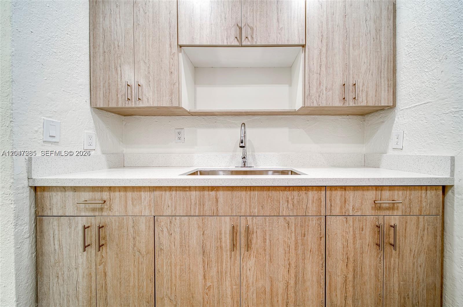 A wet bar features light wood-grain cabinets, a white countertop, and a stainless steel sink — 1747 NW 40th St # 1747, Miami FL 33142, MIAMI, FL