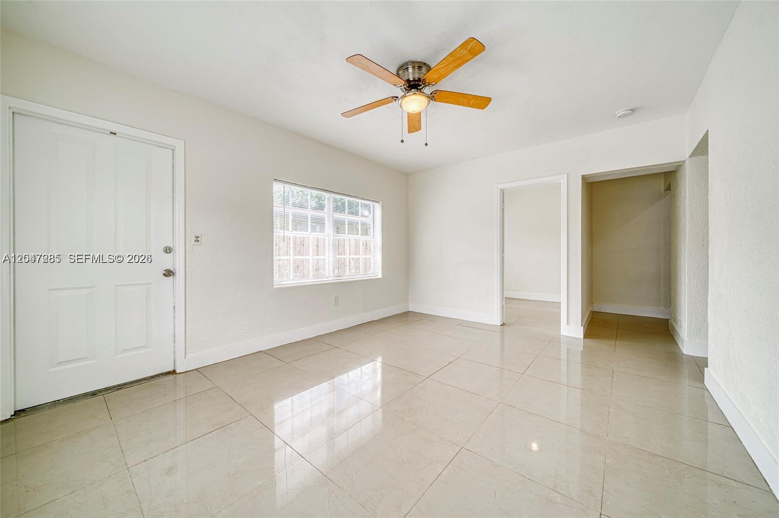 An empty room features white walls, large beige floor tiles, and a ceiling fan — 1747 NW 40th St # 1747, Miami FL 33142, MIAMI, FL